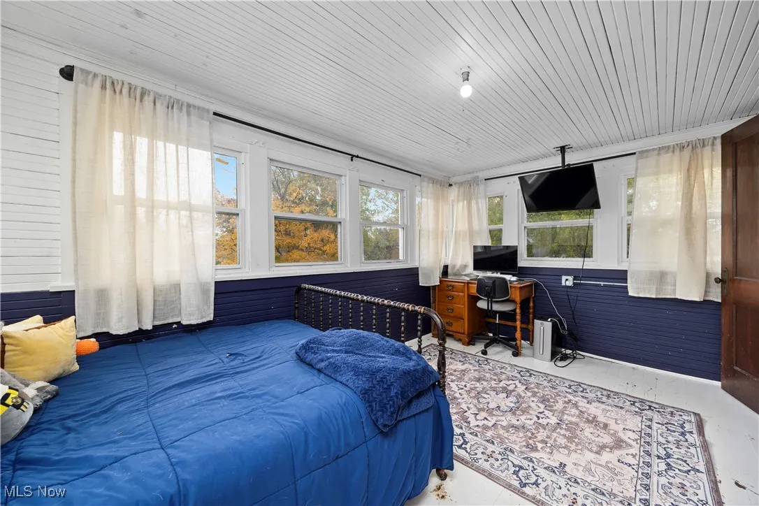 Bedroom featuring concrete floors, wooden walls, a desk, and wood ceiling