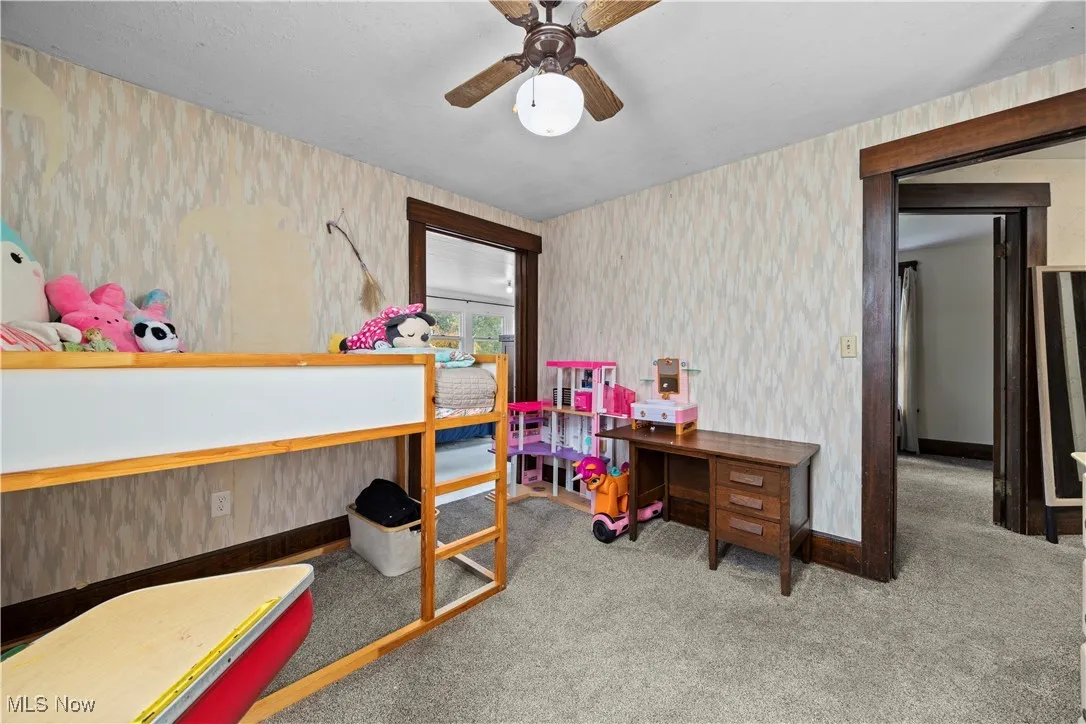 Bedroom featuring light carpet, wallpapered walls, and ceiling fan