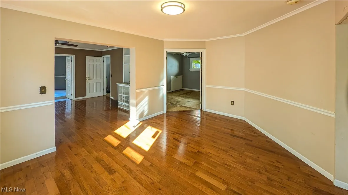 Empty room featuring wood finished floors, ornamental molding, and a ceiling fan