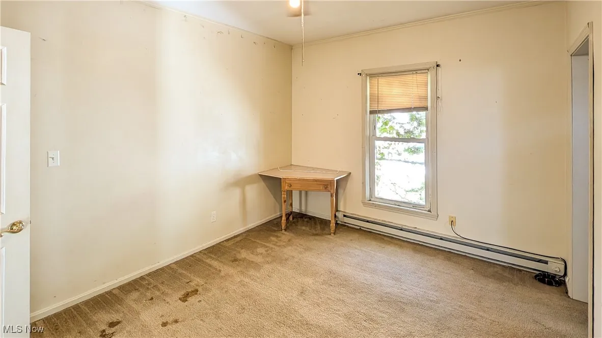 Carpeted spare room featuring a baseboard heating unit and baseboards