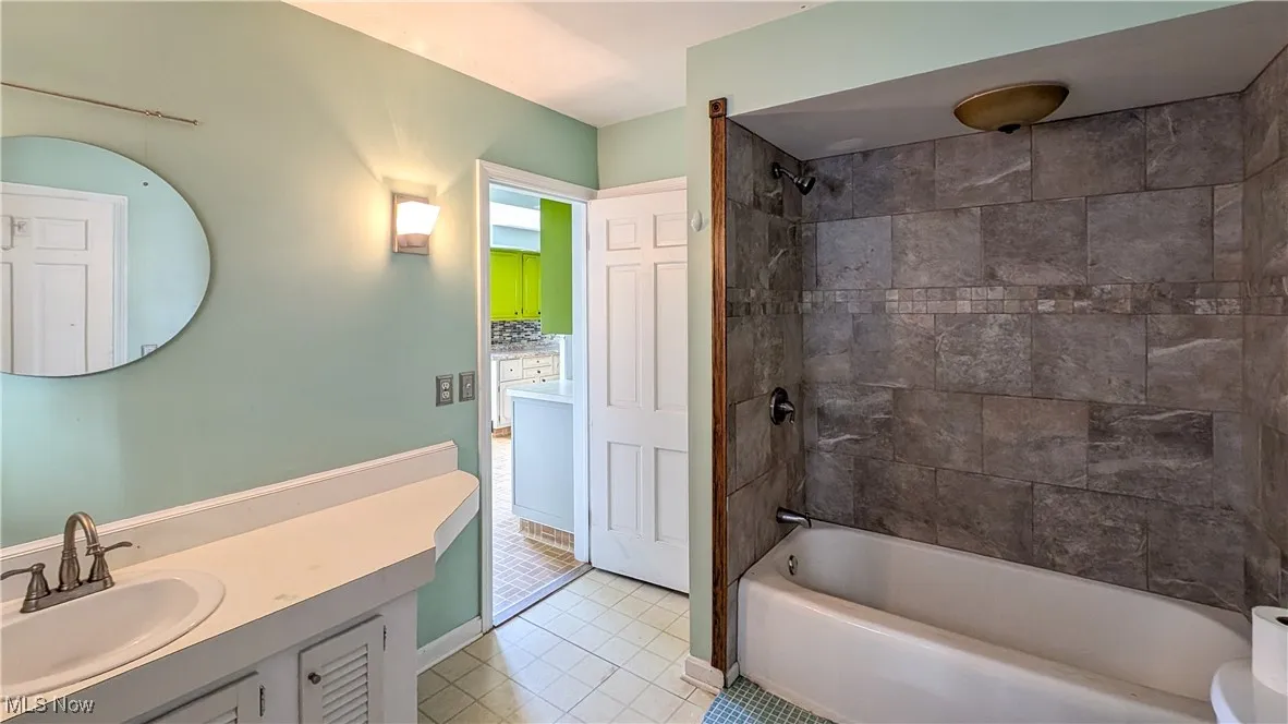 Bathroom featuring light tile patterned floors, shower / bathtub combination, vanity, and decorative backsplash