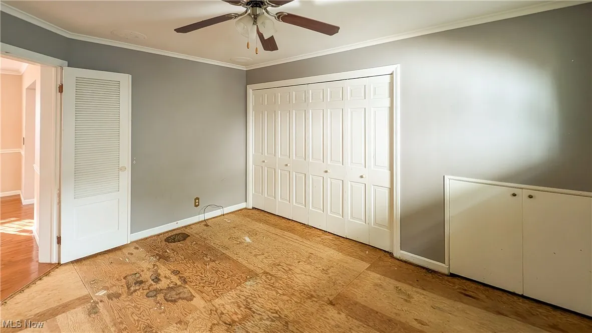 Unfurnished bedroom with crown molding, a closet, and ceiling fan