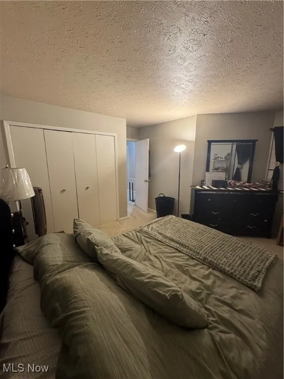 Carpeted bedroom featuring a closet and a textured ceiling