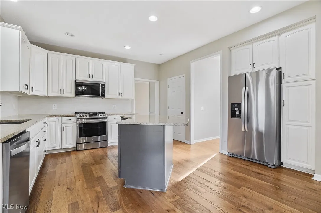 Kitchen featuring recessed lighting, appliances with stainless steel finishes, tasteful backsplash, white cabinets, and light wood-type flooring