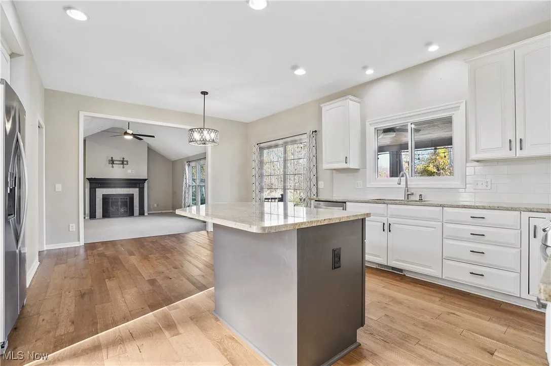 Kitchen with white cabinets, a tiled fireplace, pendant lighting, plenty of natural light, and lofted ceiling