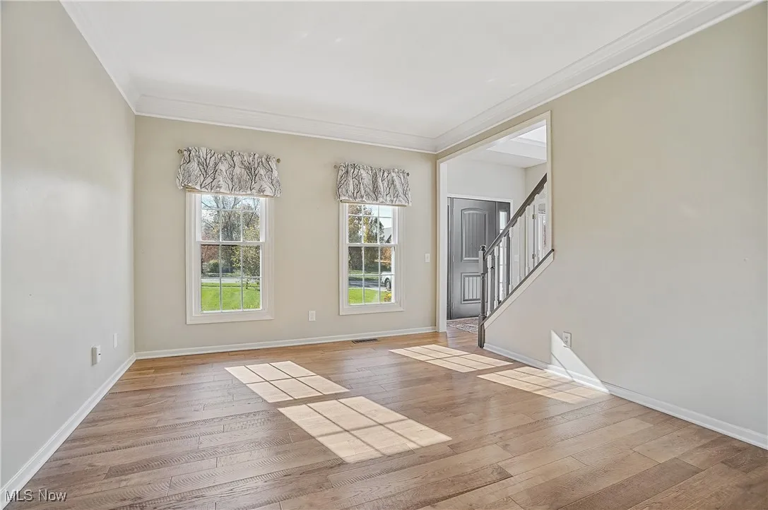 Unfurnished room featuring ornamental molding, stairs, and light wood finished floors