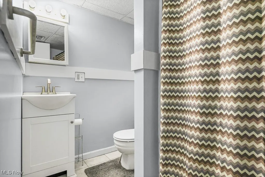 Full bathroom with light tile patterned flooring, a drop ceiling, vanity, and curtained shower