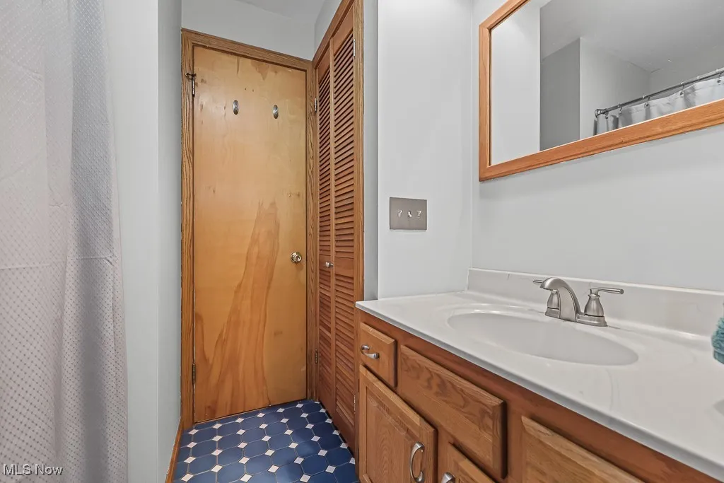 Full bathroom featuring a shower with curtain, vanity, and a closet