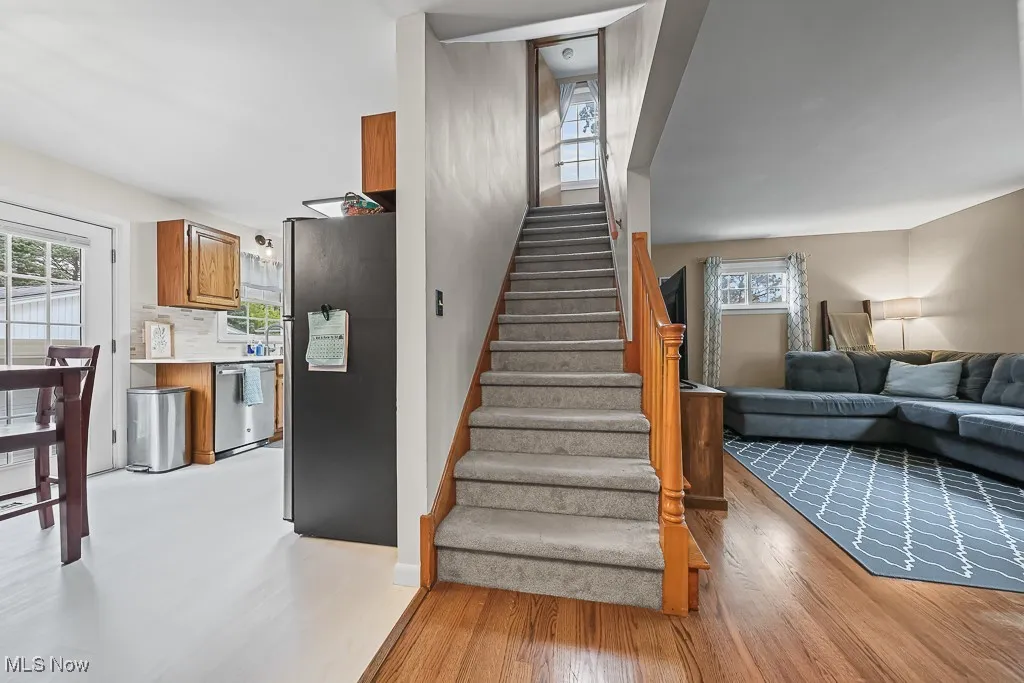 Stairs with healthy amount of natural light and wood finished floors