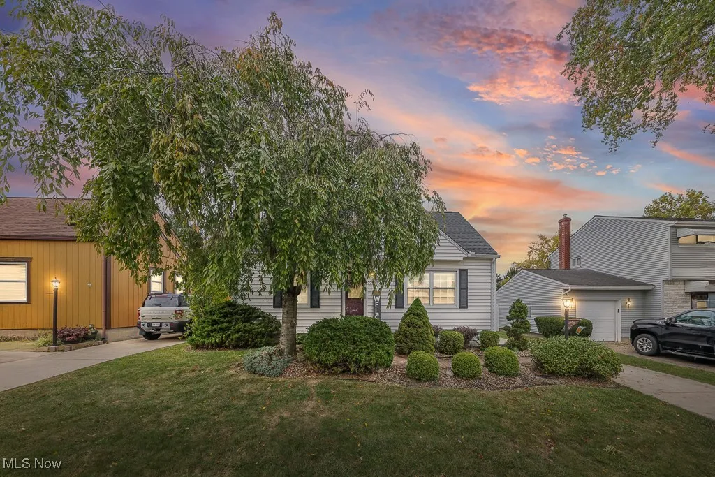 View of property hidden behind natural elements with a front lawn