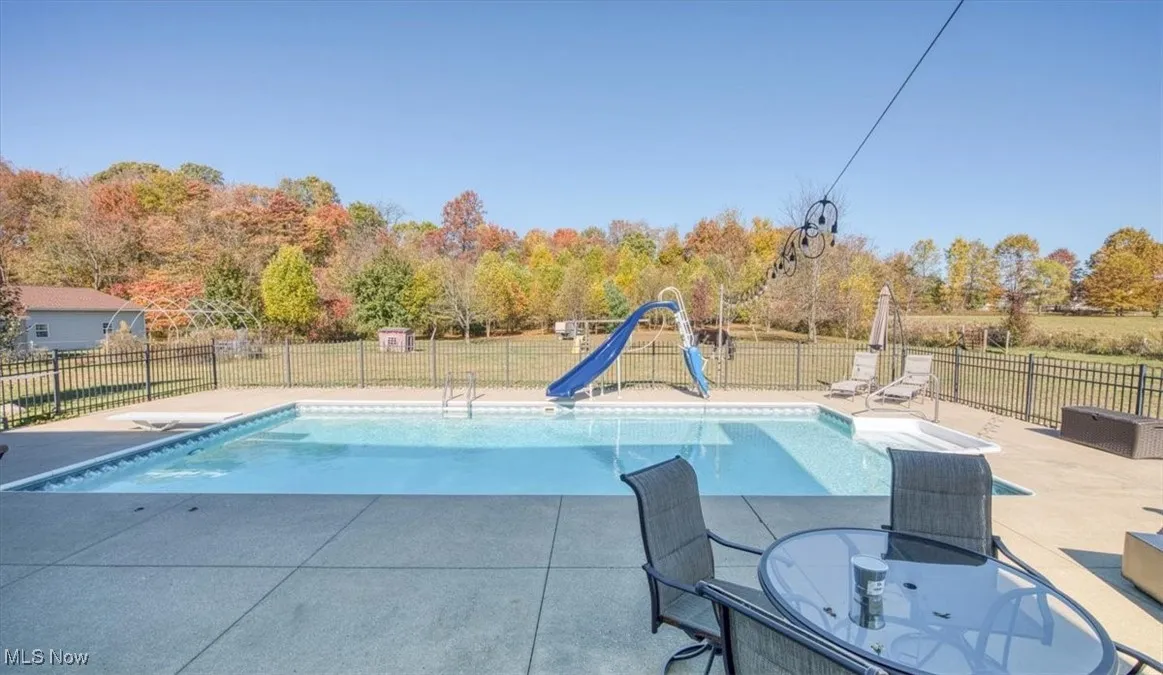 View of pool with a water slide, a patio, and a diving board