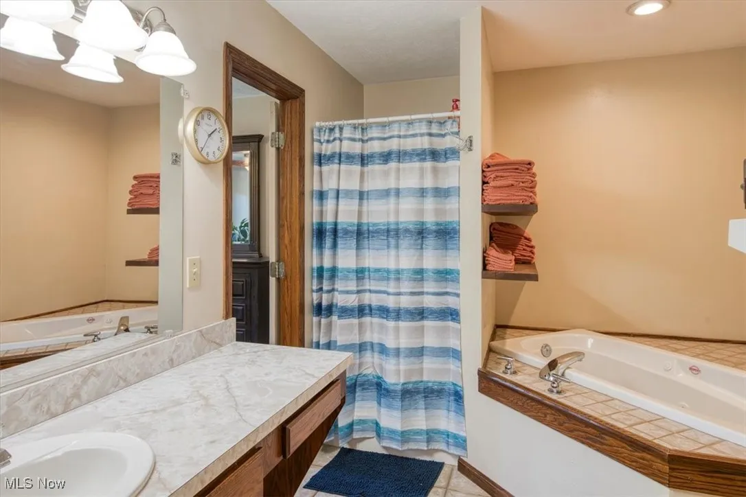 Bathroom with a garden tub, vanity, a shower stall, and light tile patterned floors