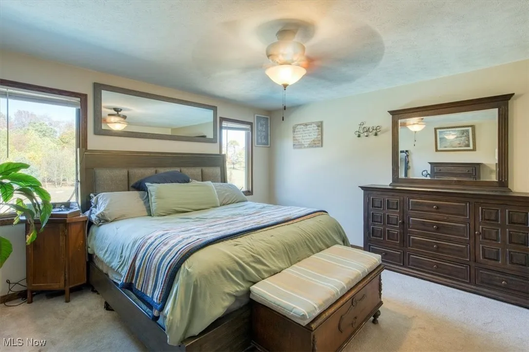 Bedroom featuring light colored carpet, a ceiling fan, and a textured ceiling