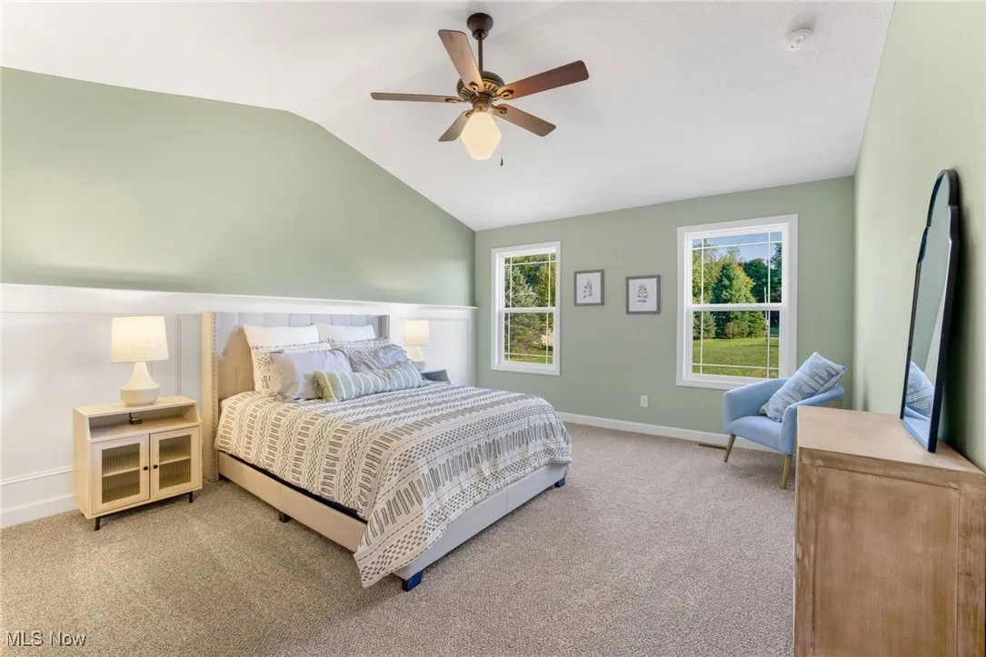 Carpeted bedroom featuring lofted ceiling and ceiling fan