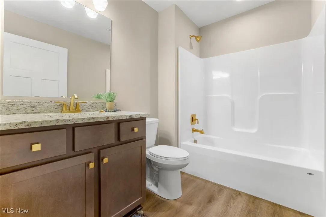Full bathroom featuring washtub / shower combination, vanity, toilet, and wood-type flooring