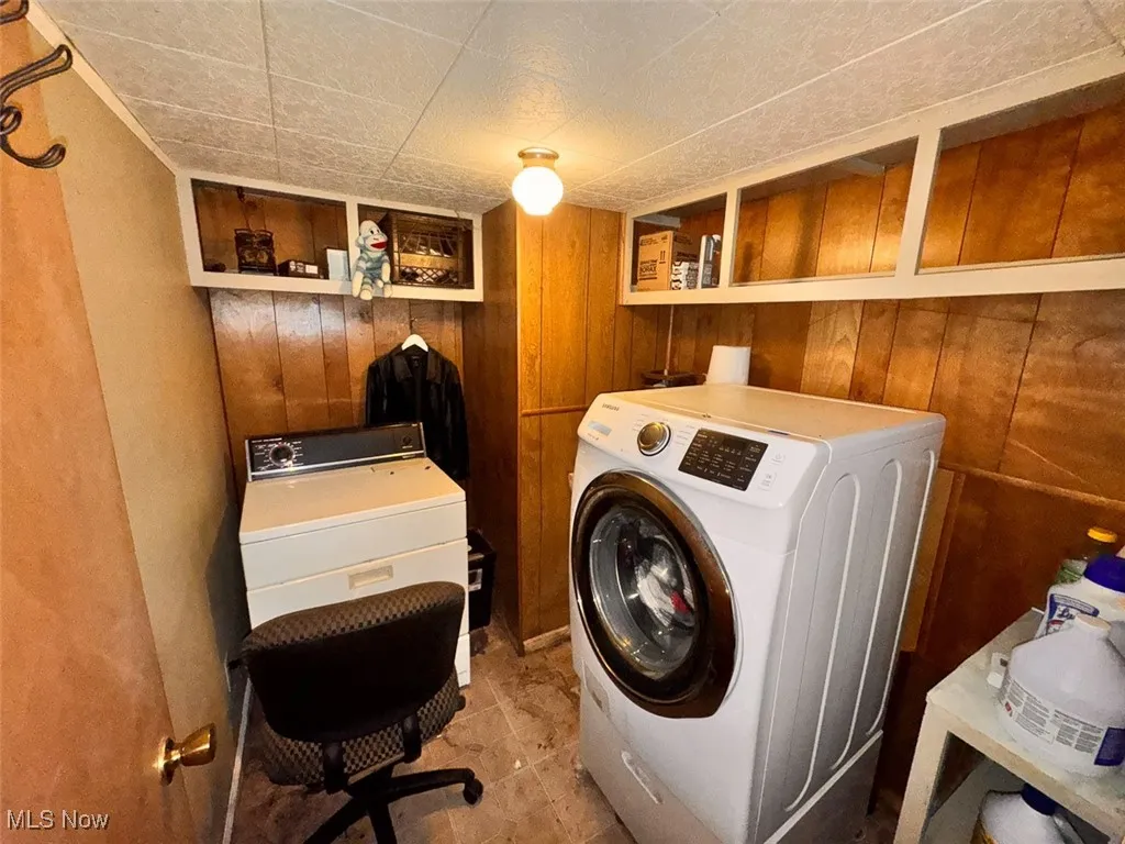 Laundry room with independent washer and dryer and wood walls