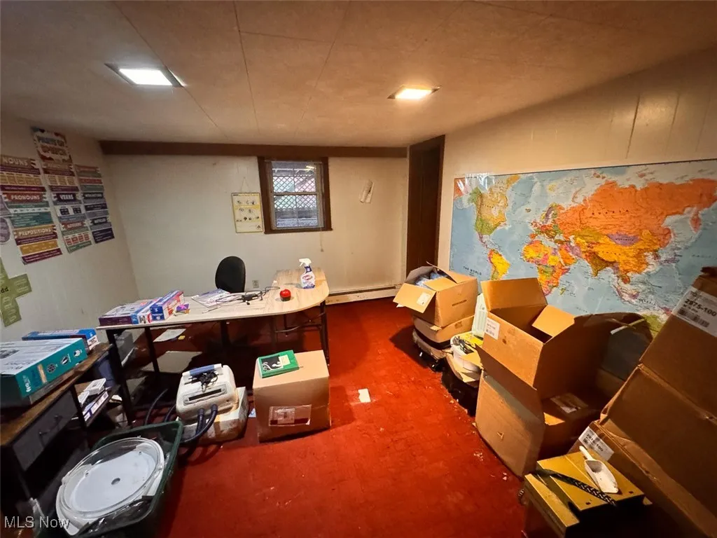Basement featuring dark colored carpet and baseboard heating