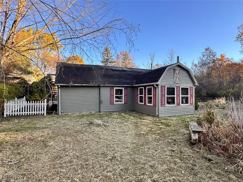 Rear view of house featuring a shingled roof and a gambrel roof