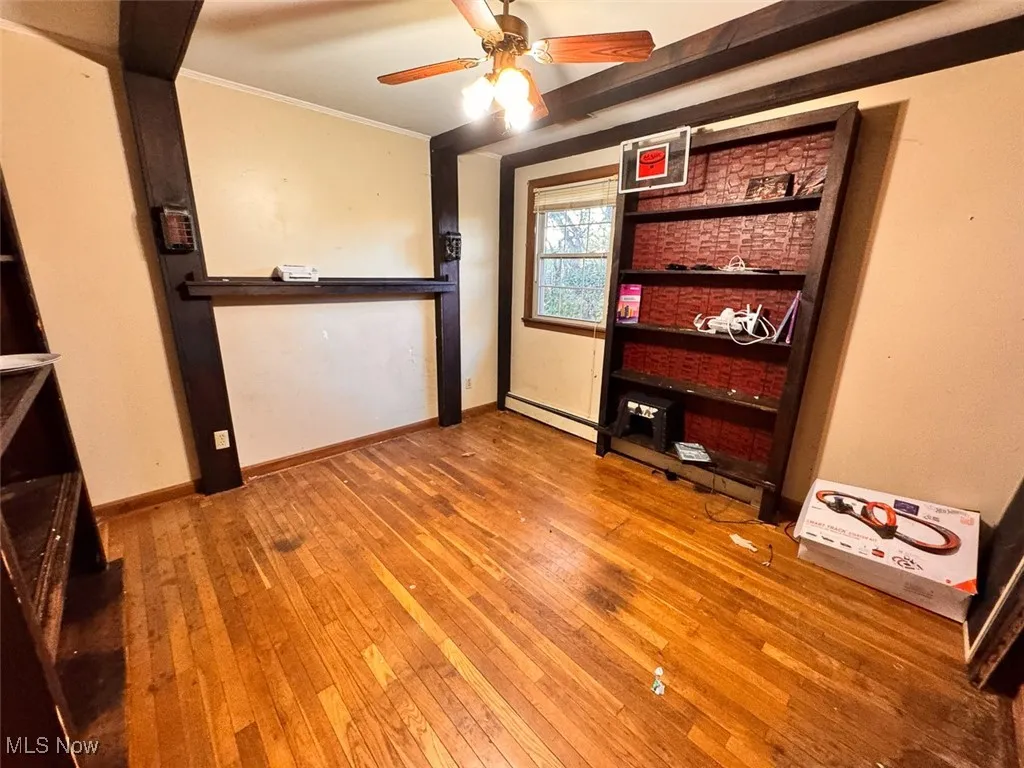 Spare room featuring light wood-style floors, ornamental molding, a baseboard radiator, and a ceiling fan
