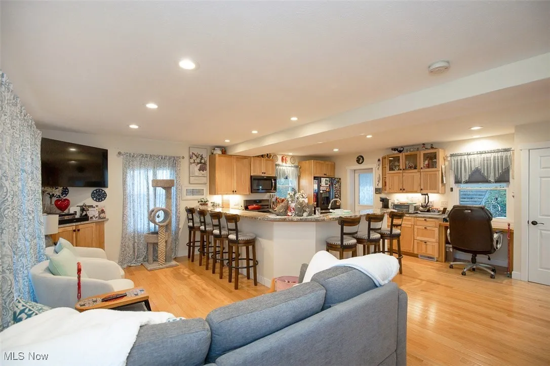 Living room featuring maple wood floors, recessed lighting, and a desk