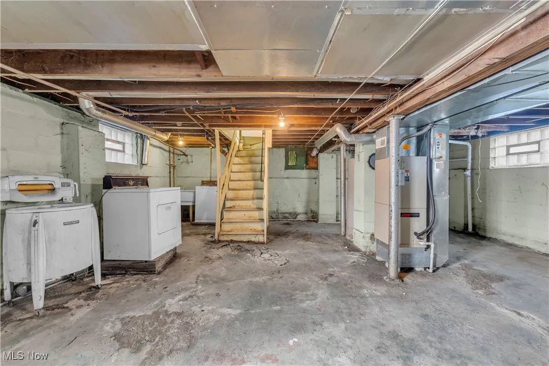 Basement featuring stairway and heating unit