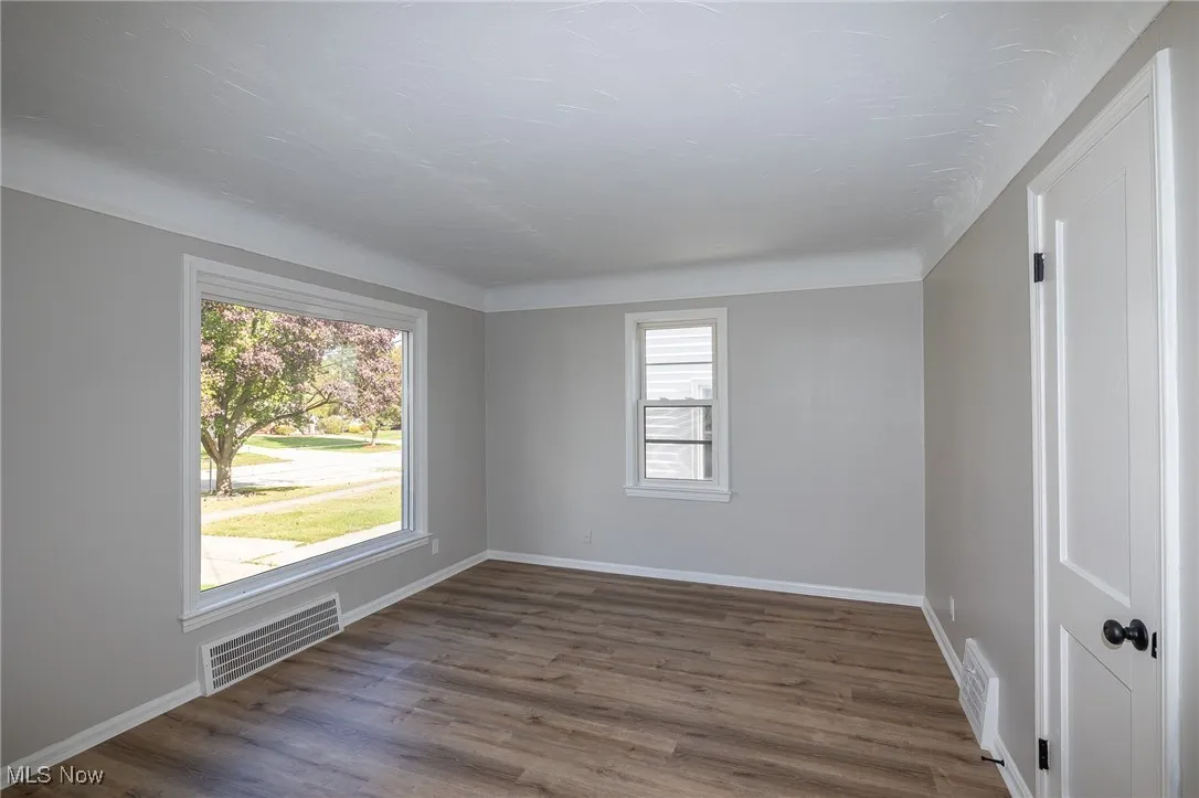 Spare room featuring dark wood-type flooring and baseboards