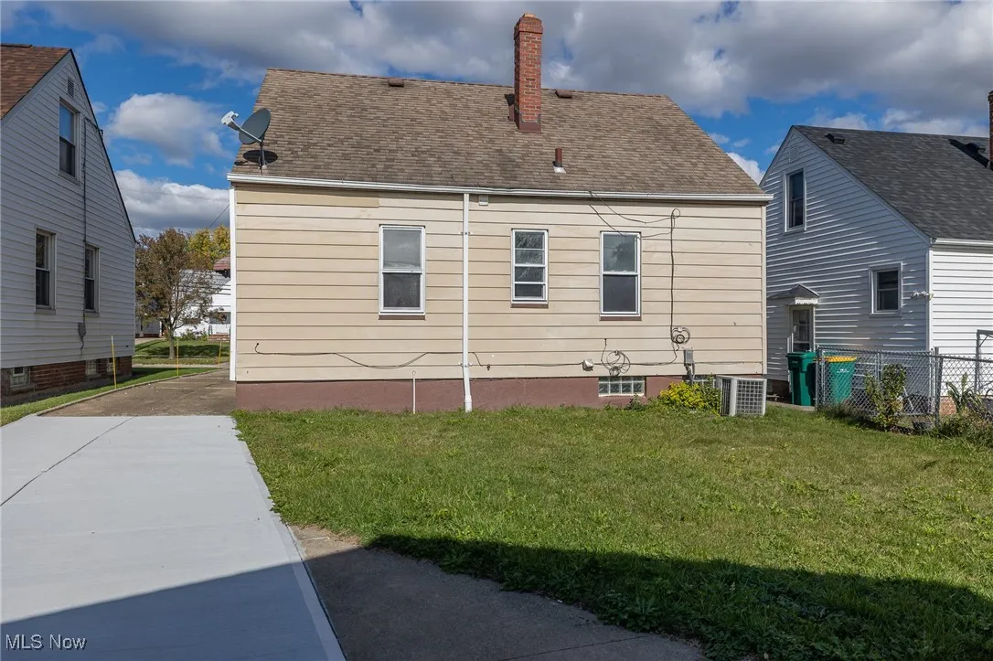 Rear view of property with a chimney, a yard, and a shingled roof