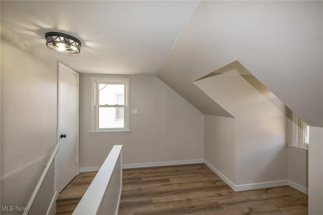 Additional living space with healthy amount of natural light, light wood-style flooring, and vaulted ceiling