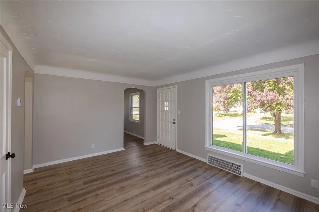 Foyer entrance featuring arched walkways, wood finished floors, and healthy amount of natural light