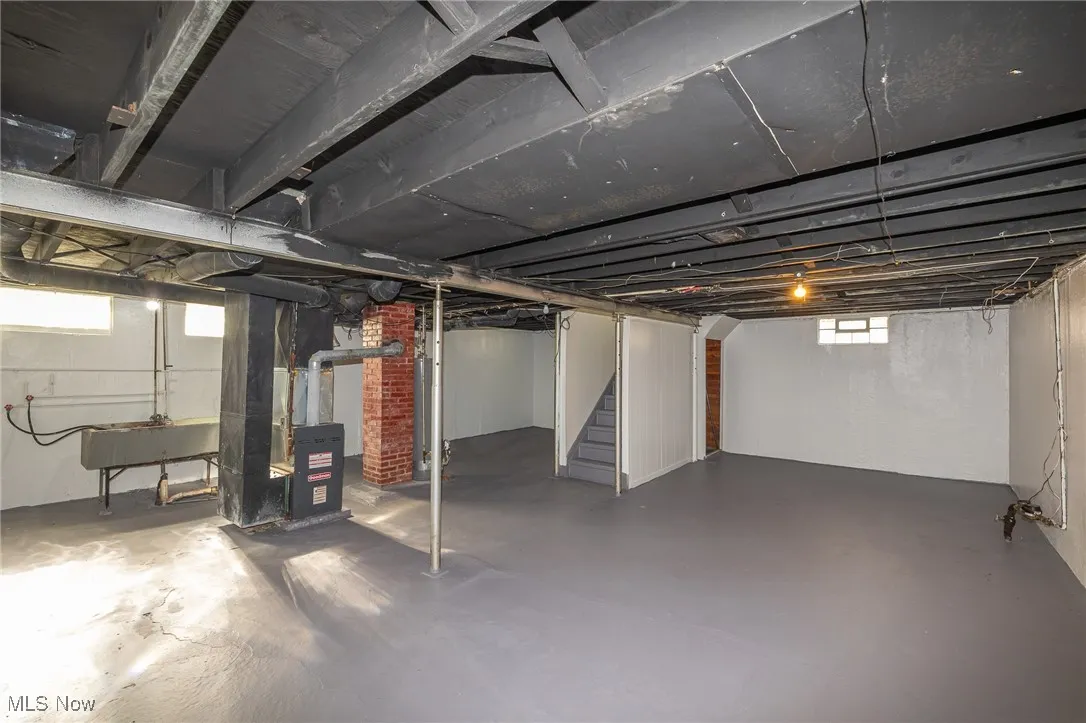 Below grade area featuring stairs and heating unit