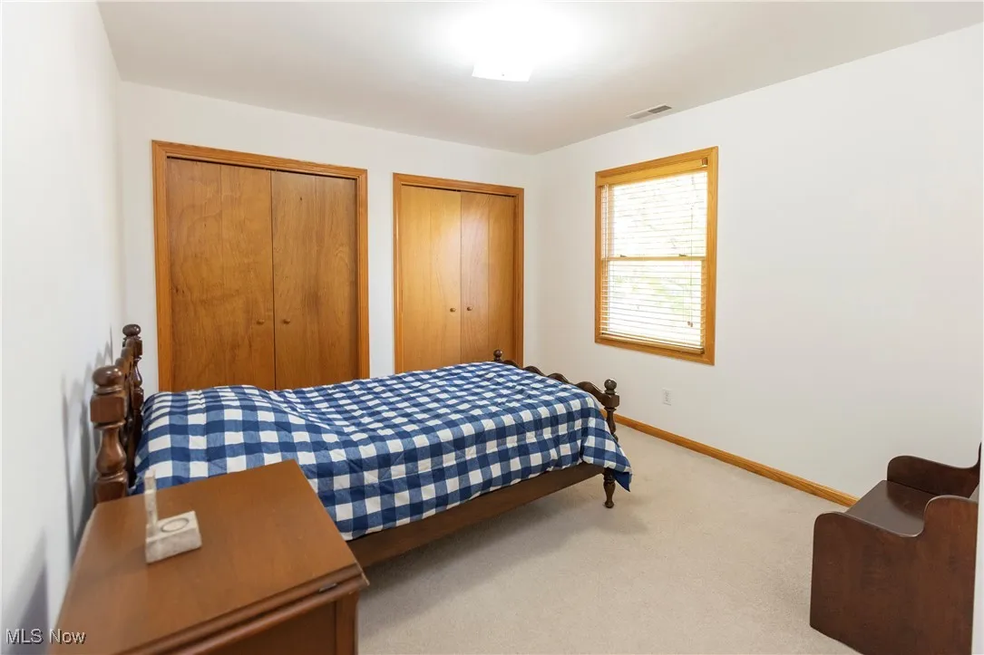 Bedroom featuring light colored carpet and two closets