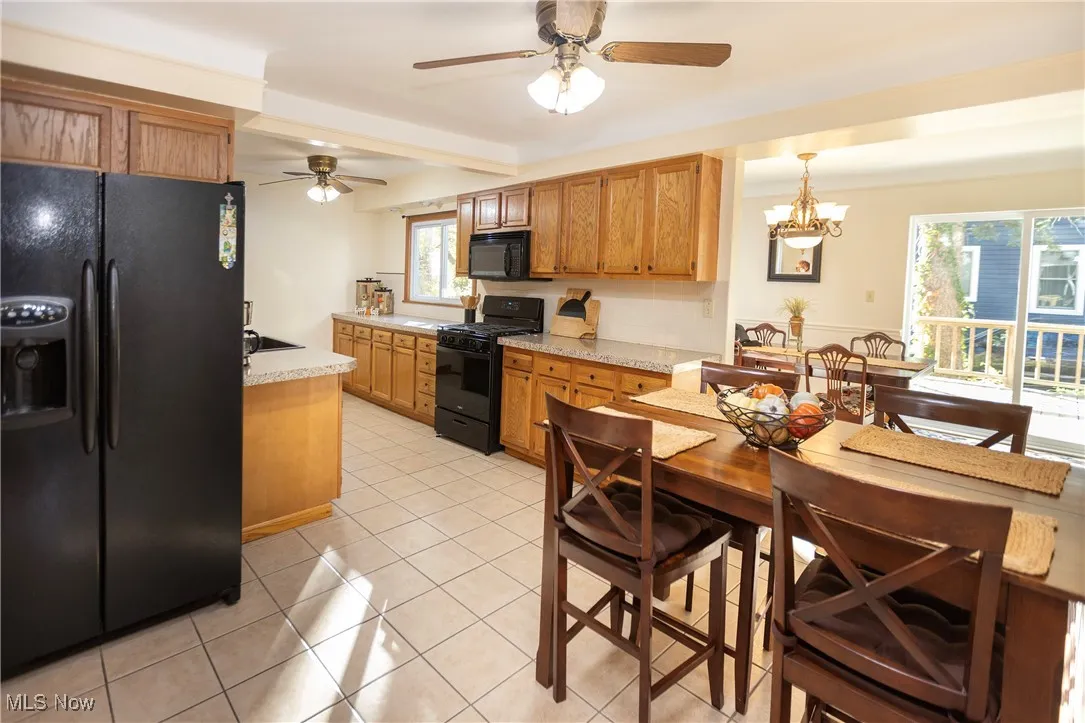 Kitchen featuring black appliances, light countertops, a ceiling fan, light tile patterned floors, and a chandelier