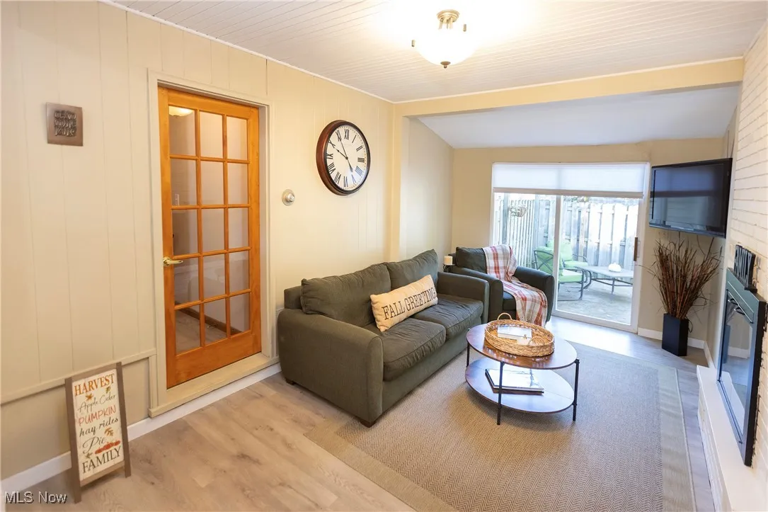 Living area featuring wood finished floors, a large fireplace, and wooden walls