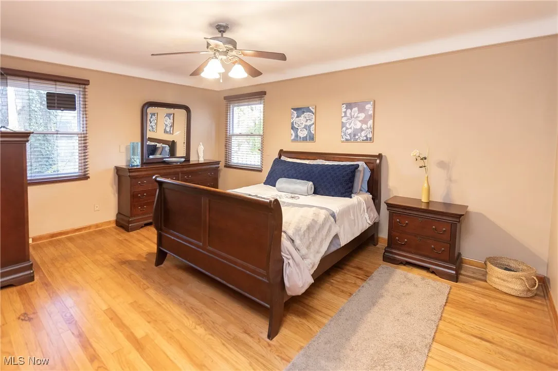 First floor bedroom with light wood-type flooring, ceiling fan and large closet