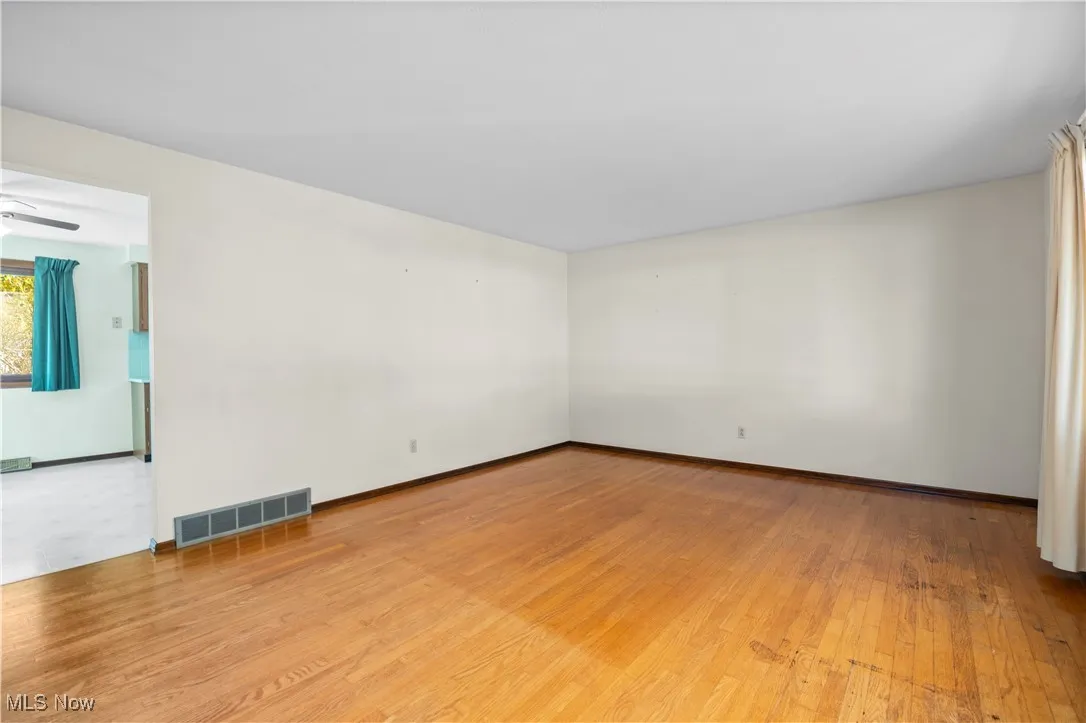 Living room with original hardwood floors looking into dining area