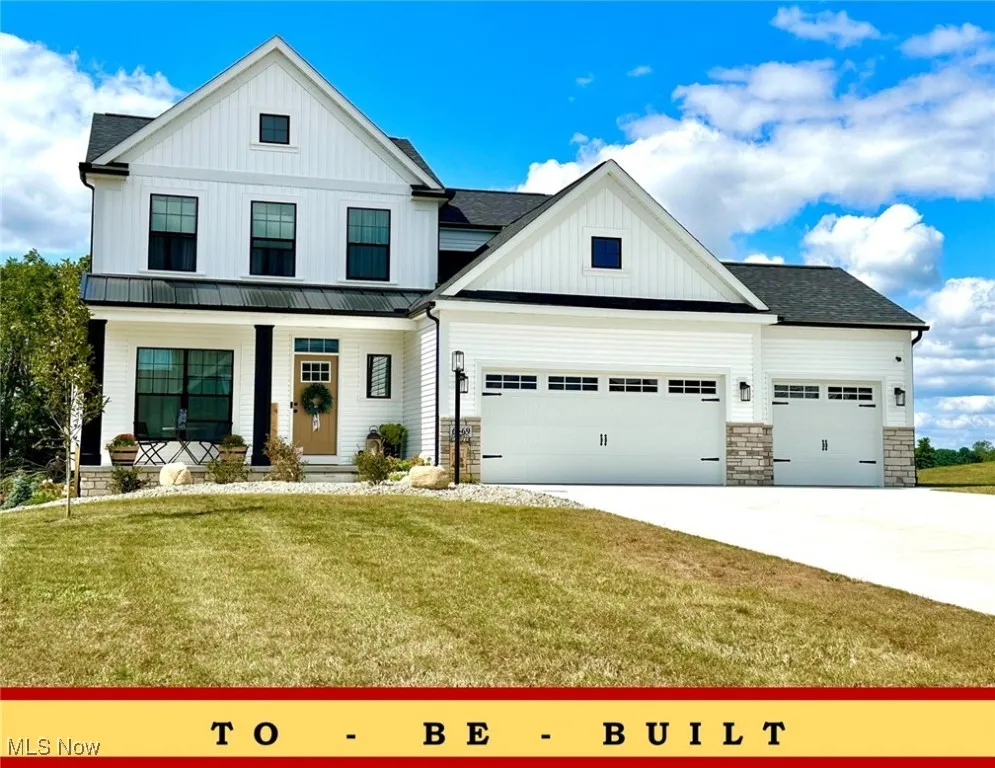Modern farmhouse style home with a front yard, stone siding, concrete driveway, and board and batten siding