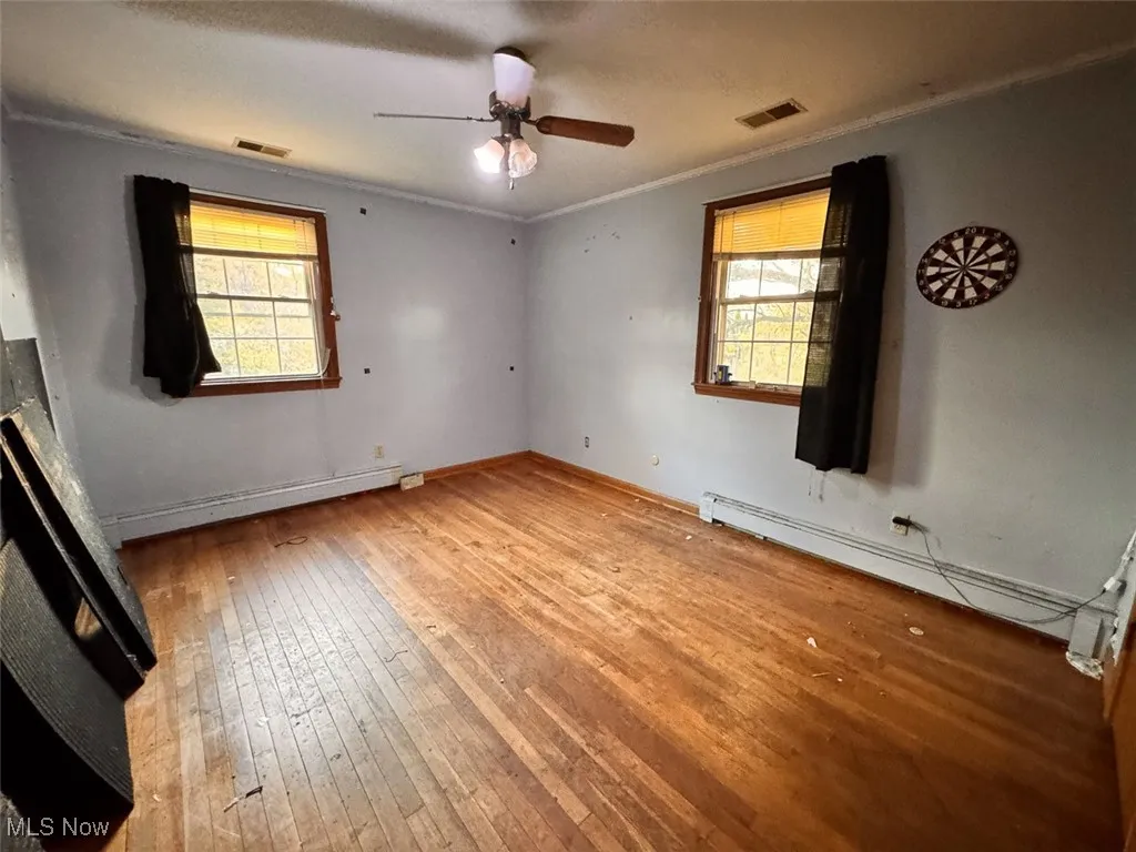 Bedroom with crown molding, light wood finished floors, a baseboard radiator, and ceiling fan