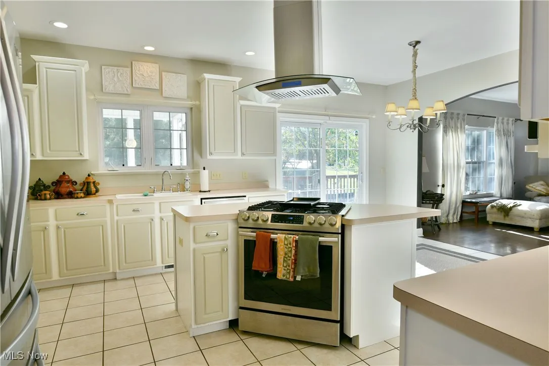 Kitchen featuring stainless steel appliances, island exhaust hood, light countertops, plenty of natural light, and recessed lighting