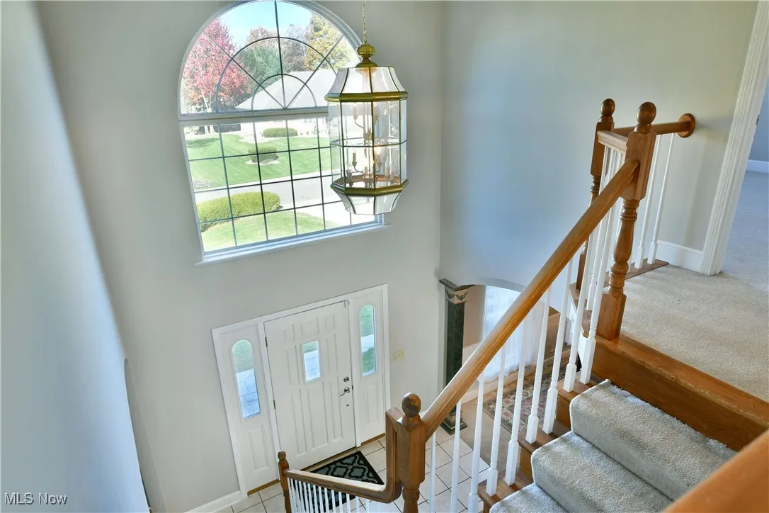 Entryway featuring stairs, a high ceiling, and light colored carpet
