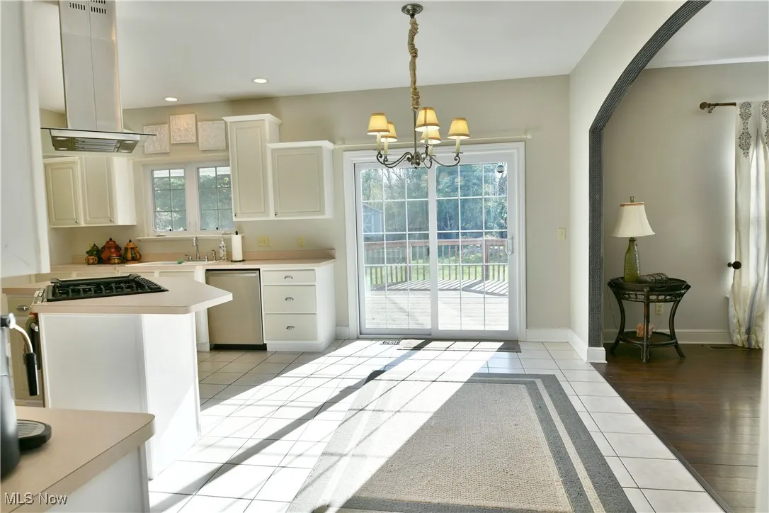 Kitchen with light tile patterned flooring, light countertops, island exhaust hood, plenty of natural light, and recessed lighting