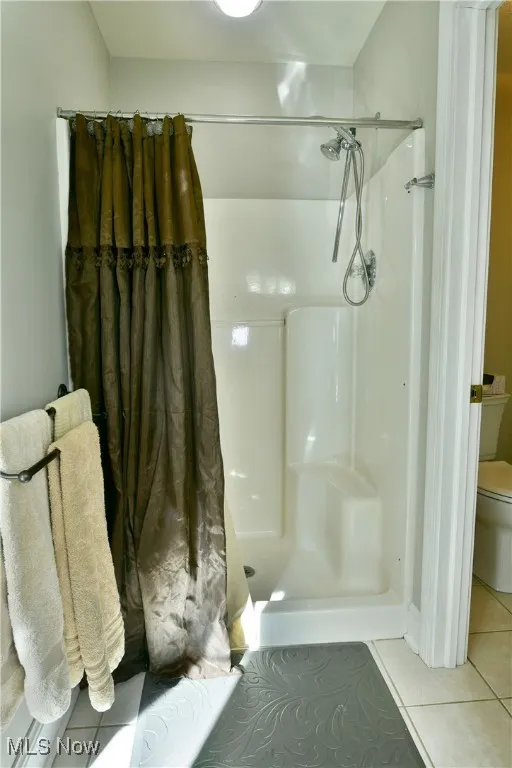Bathroom featuring tile patterned floors and a shower stall