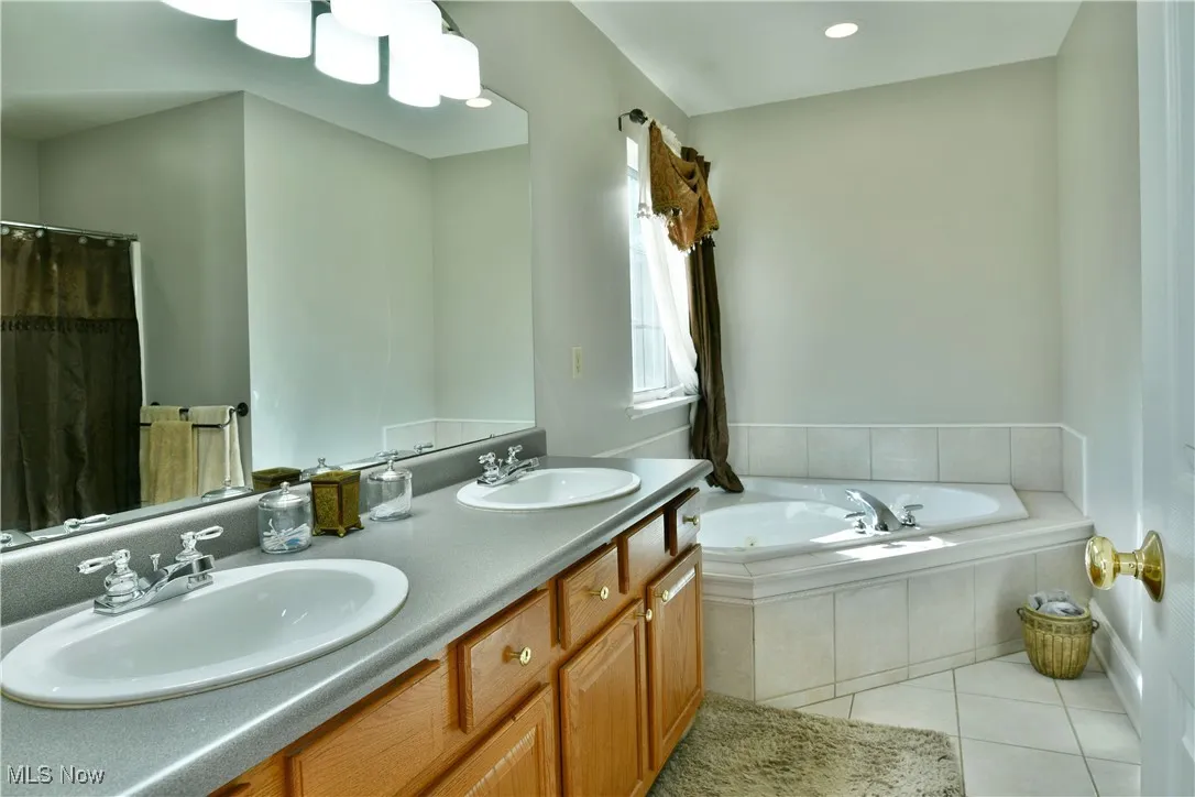 Full bathroom featuring light tile patterned floors, double vanity, a bath, a shower with curtain, and recessed lighting