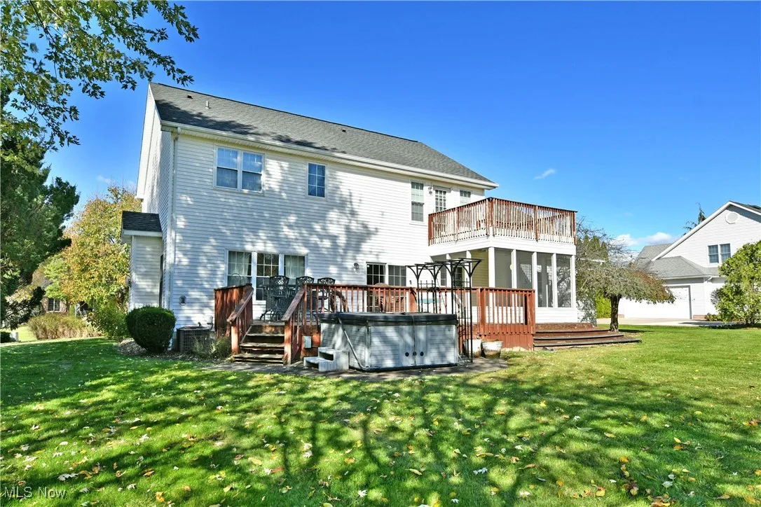 Rear view of property with a yard, a deck, and a hot tub