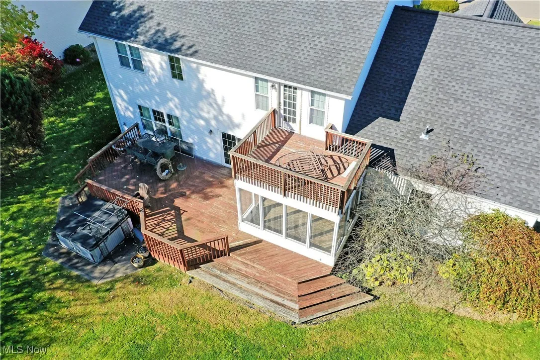 Rear view of property featuring a deck, roof with shingles, and a sunroom