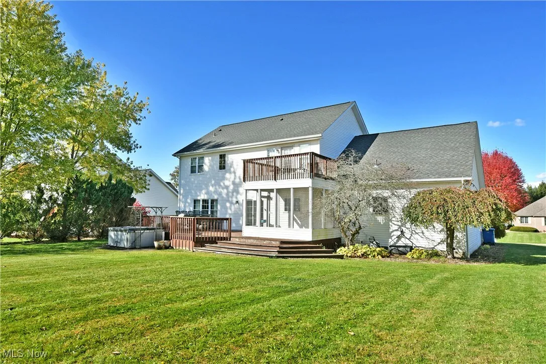 Rear view of property featuring a wooden deck, a yard, a balcony, and roof with shingles