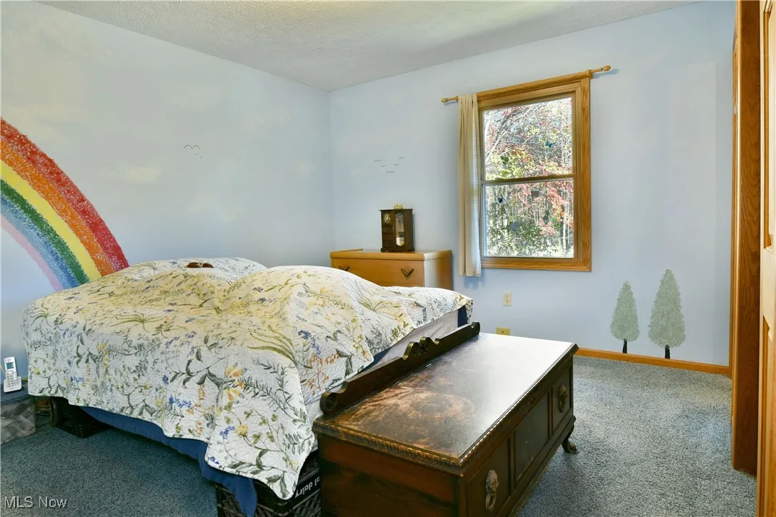 Carpeted bedroom featuring baseboards and a textured ceiling