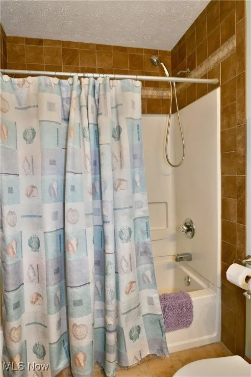 Full bathroom with shower / bath combo, a textured ceiling, and tile patterned flooring