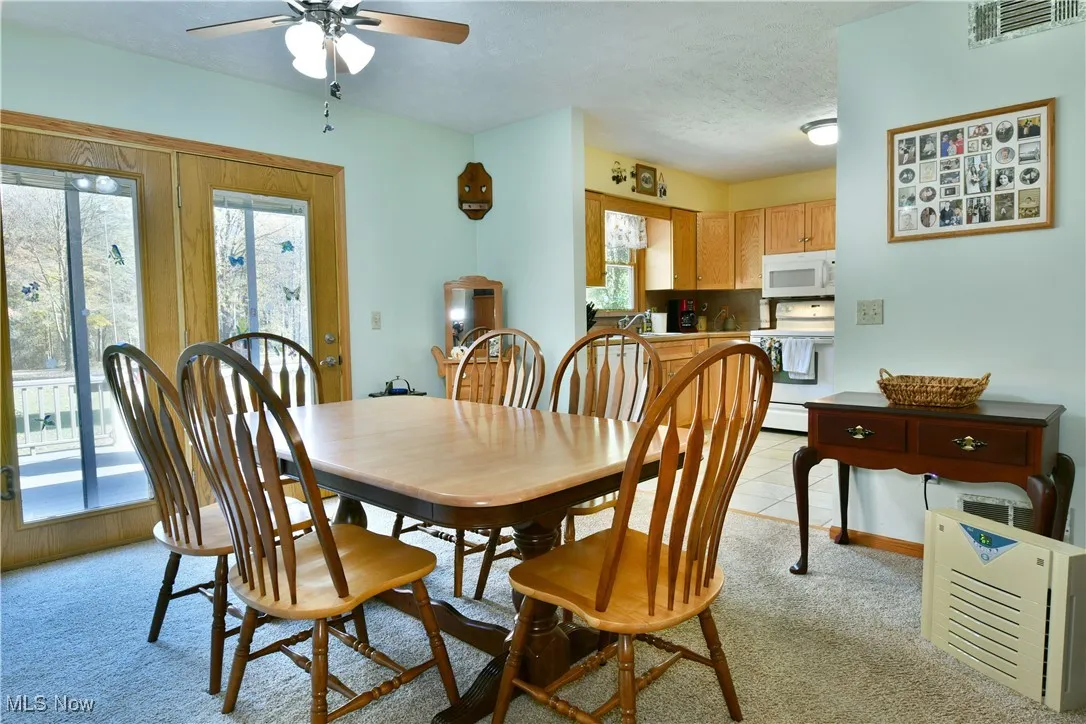 Dining area with light colored carpet, a textured ceiling, and ceiling fan