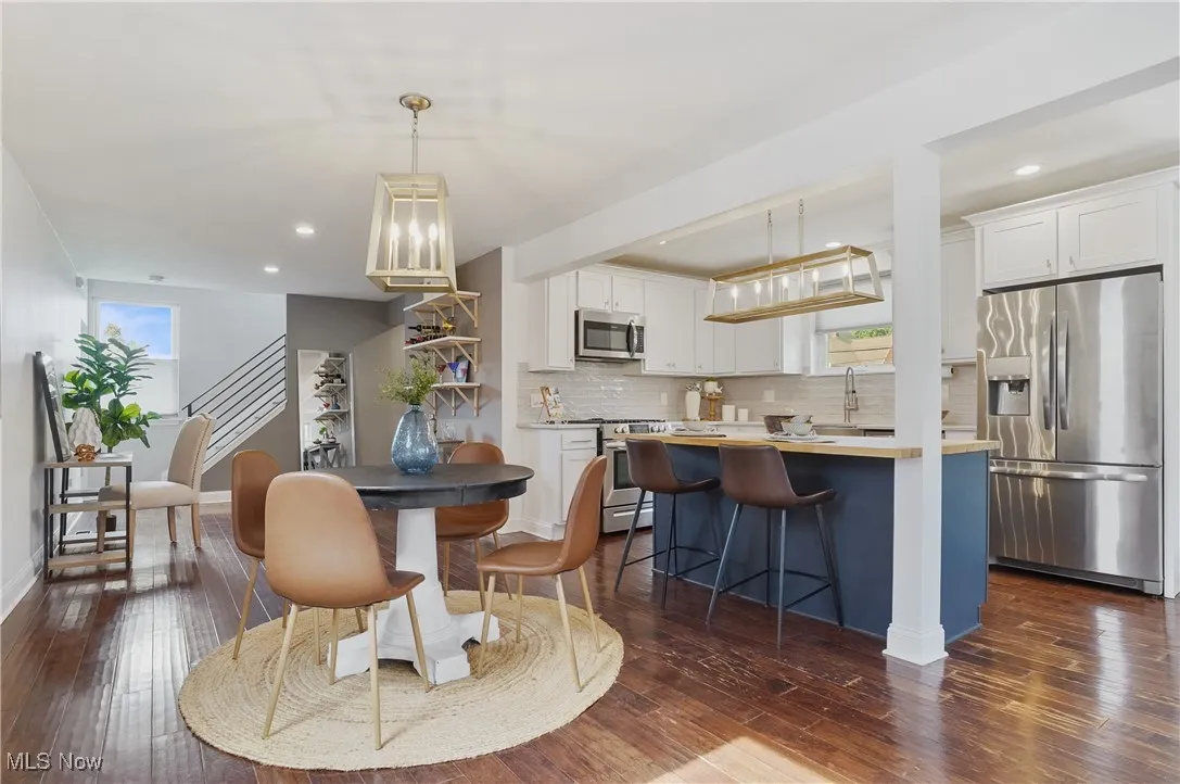 Dining room with dark wood-style floors, recessed lighting, and stairway