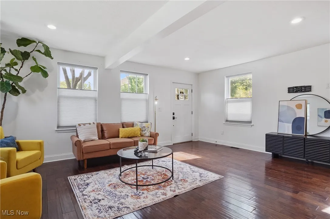 Living area with dark wood finished floors, recessed lighting, and beam ceiling